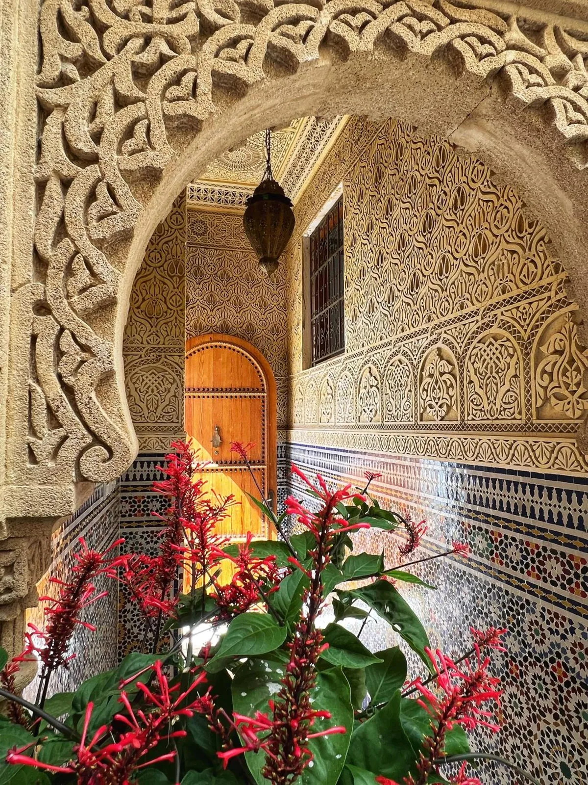 L'arc en plâtre sculpté et les fleurs rouges du patio